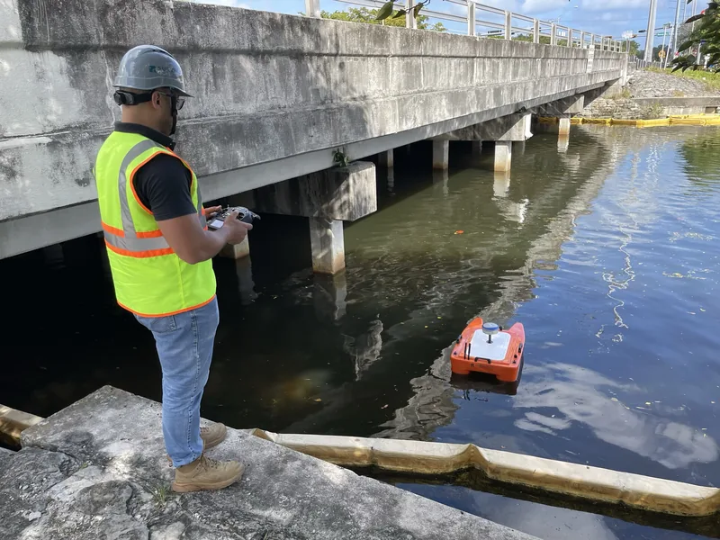 SurveyFy surveyor piloting the unmanned survey boat for a bathymetric survey under a bridge