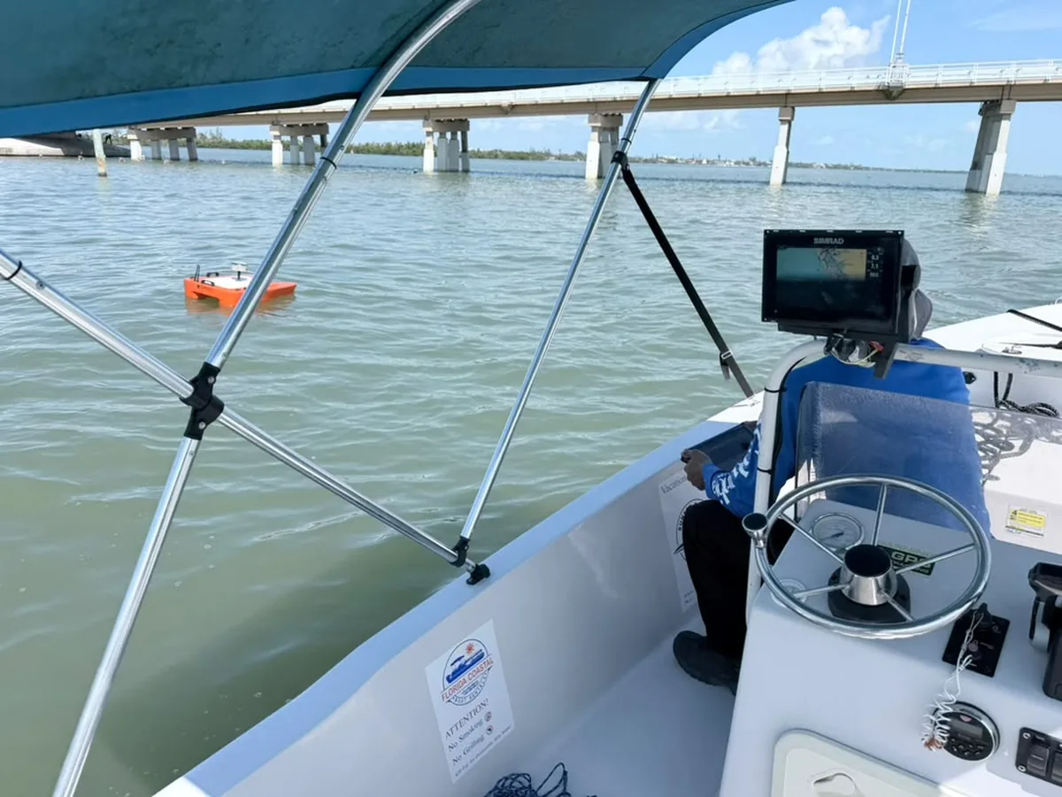 SurveyFy crew operating an unmanned survey boat for a bathymetric survey near a bridge