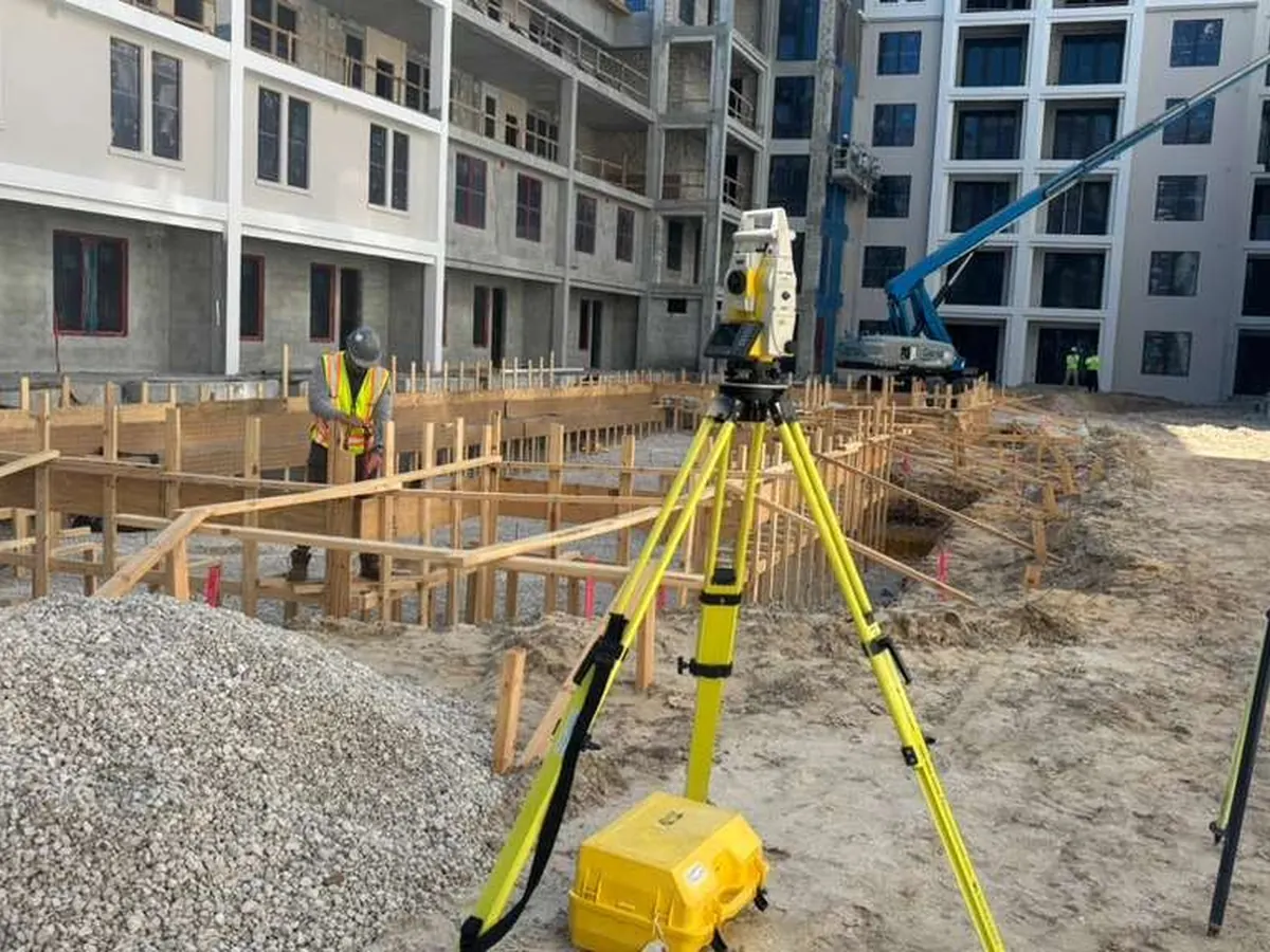 Robotic total station in front of a building foundation with formwork in Florida