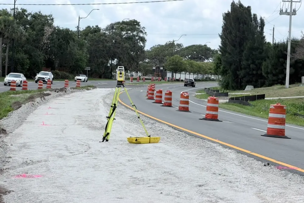 SurveyFy total station set up on a roadway under construction with traffic cones
